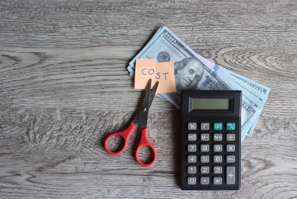 scissors cutting the word cost with calculator and money