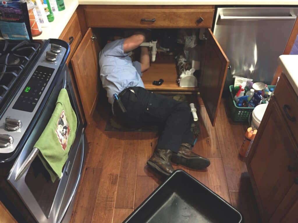 plumber working under kitchen sink